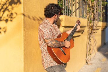 Latin adam gün batımında şehir sokaklarında gitar çalıyor.