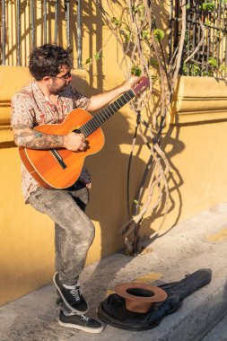 Genç adam sokakta gitar çalıyor.