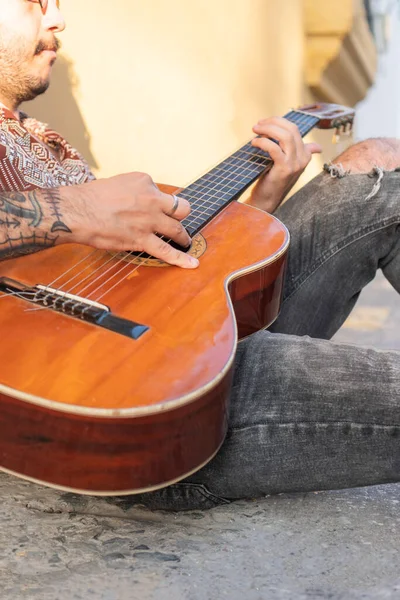 Street musician\'s hands playing guitar in the street