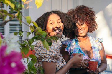 Dışarıda kahve içen, eğlenen ve konuşan iki kadın.