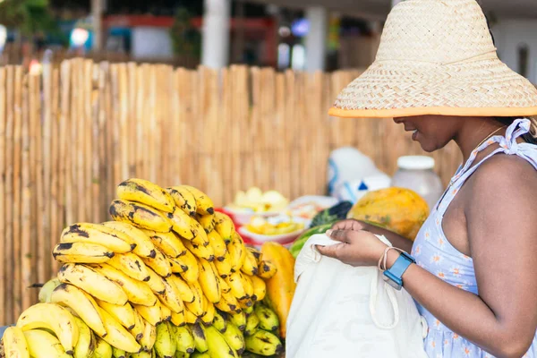 Tekrar kullanılabilir bir alışveriş torbasında meyve ve sebze alan bir kadın..