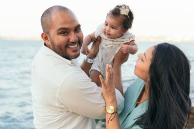 Bebeklerini kucağındayken ve sevecen davranırken bir ailenin portresi..