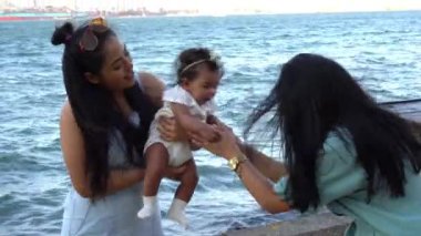 Latin anne ve kız kardeşi, bebeğini havaya kaldırıyor.