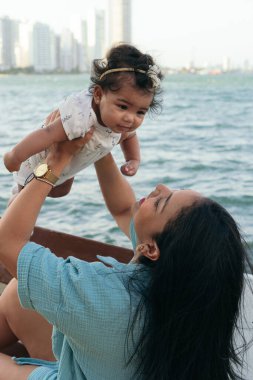 Latin Anne bebeğini havaya kaldırıyor.