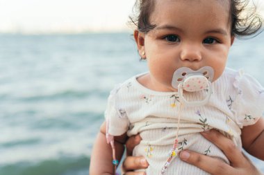 Parkta emziği olan bir bebek.