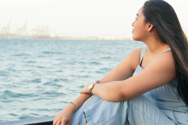 若い女性が桟橋に座って夏の日に集中して — ストック写真