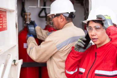 Telefon üzerinden koordine eden kadın mühendis, arka planda etkin takım arkadaşı