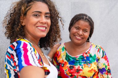 İki eski arkadaş duvarın önünde selfie çekiyorlar.