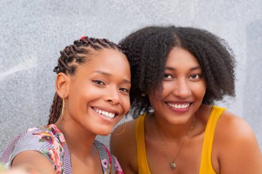 Yüzlerinde geniş bir gülümseme olan iki Afro-Amerikalı arkadaşa yakın çekim..