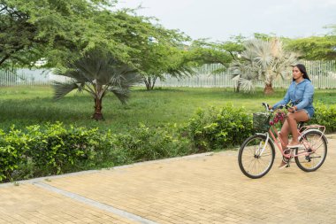 Şehir parkında bisiklet süren genç bir kadın.