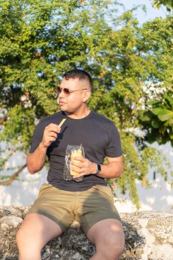 Sıradan bir adam dışarıda oturmuş buzlu şekerin tadını çıkarıyor, doğal yeşil zemin..