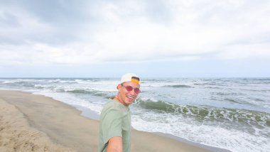 Güneşli sahilde güneş gözlüklü bir adam.