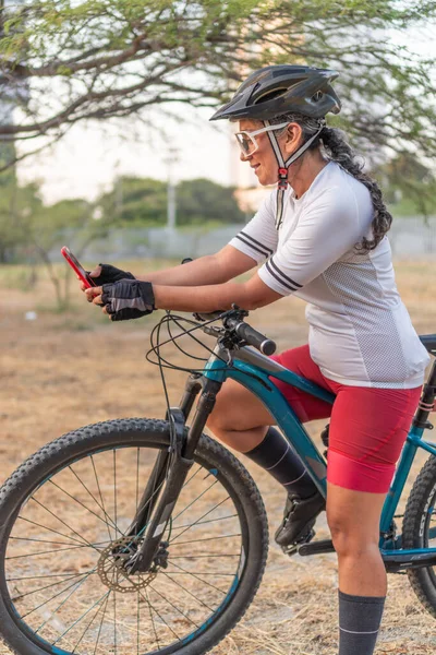 Latin Woman cyclist checking smartphone during a ride