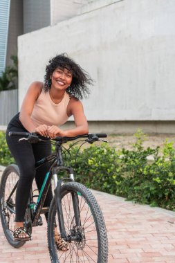 Neşeli kadın şehirde bisiklet sürmekten zevk alıyor.