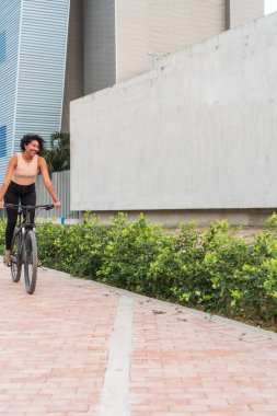 Gülümseyen kadın şehir yolunda bisiklet sürmekten hoşlanıyor