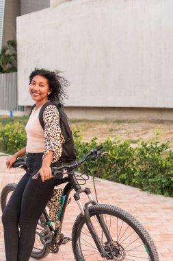 Bisikletli Latin Kadın şehirde güneşli bir günün tadını çıkarıyor.