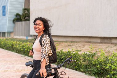 Bisikletli bir kadın güneşli bir günde şehirde eğleniyor.