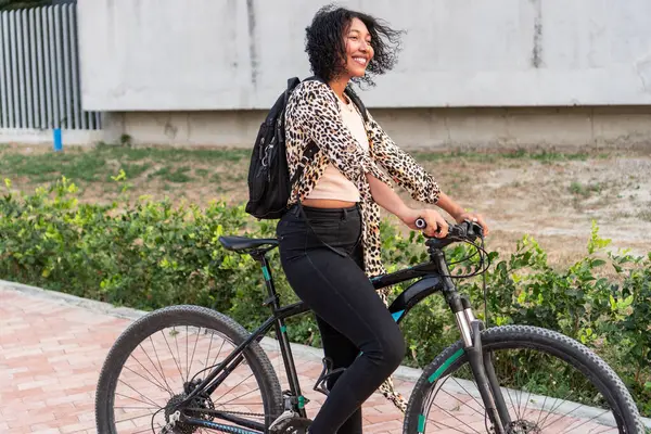 Şık kıyafetli, bisikletli, gülen kadın.