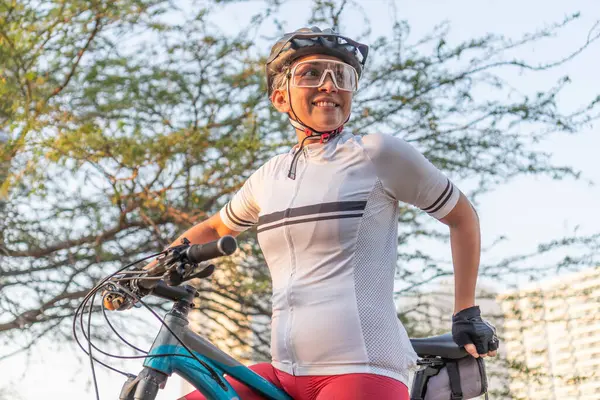 A low-angle shot of a smiling woman with a bicycle, looking into the distance.
