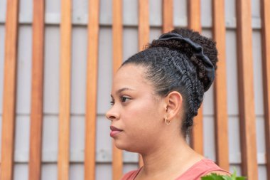 Bakkaliye ile genç bir kadının yan profili, gevşek ahşap bir arka plana karşı düşüncelere dalmış..