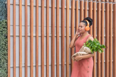 Kulaklıklı ve Bakkaliyeli Latin Kadın Çağrının tadını çıkarıyor