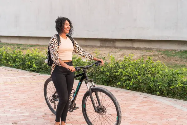 Bisiklet gidonunu tutan mutlu genç bir kadın, şık bir leopar desenli hırka giymiş..