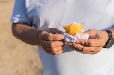 Elinde yarısı yenmiş bir börek tutan yaşlı bir adamın detaylı fotoğrafı..