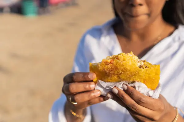 Close-up of a woman savoring a stuffed arepa, a Latin American cuisine delight.