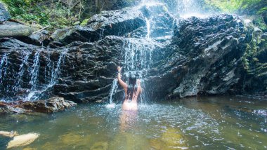 Bir kadın orman şelalesinin doğal duşundan zevk alır..