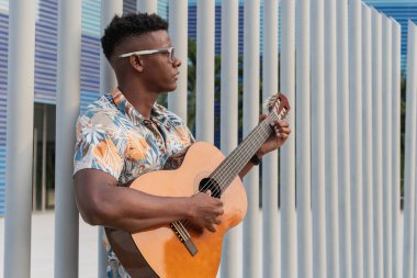 Kendine güvenen genç Afrikalı Amerikalı erkek akustik gitar çalıyor..