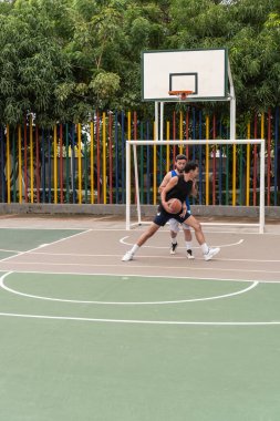 Açık hava sahasında iki adam basketbol maçında yarışıyor..