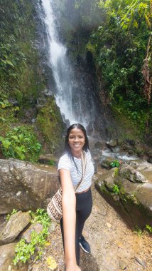 Gülümseyen kadın arka planda güzel bir orman şelalesiyle selfie çekiyor..