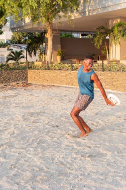 Latin Adam Sunset 'te Sandy Beach' te frizbi oynuyor.