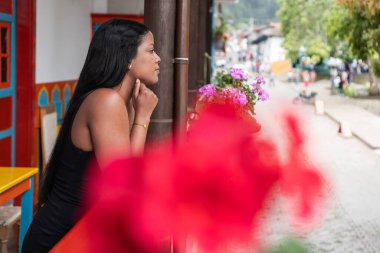 Kolombiyalı Kadın Canlı Çiçek Önplanı ile Balkondan Bakıyor