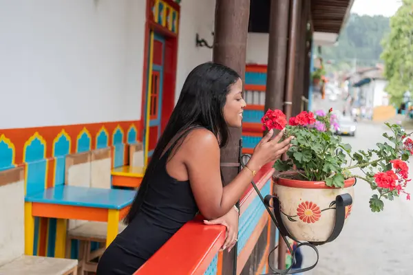 Stock image Colombian Woman Admiring Flowers on Colorful Balcony in Colombian Town