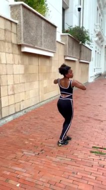 Genç şehir dansçısı taştan bir duvarın önünde modern bir koreografi sergiliyor.