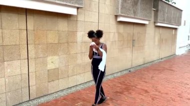 Genç şehir dansçısı taştan bir duvarın önünde modern bir koreografi sergiliyor.