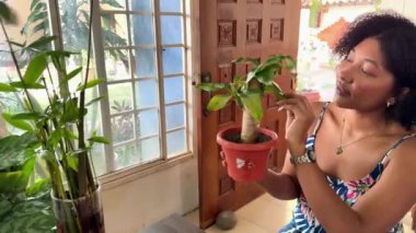 Genç bir kadın elinde küçük bir saksı bitkisi tutuyor.