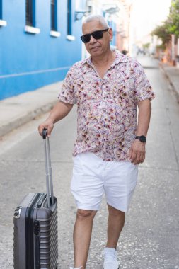 Karayipler caddesinde yürürken bavulu çeken şık bir turist.