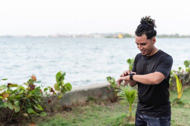 Genç Latin atlet koştuktan sonra kıyıya yakın yerleri kontrol ediyor.