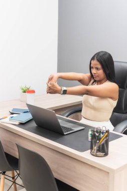 Ofis çalışanı bilek egzersizleri yapıyor, işyerinde sağlık ve sağlığı destekliyor.