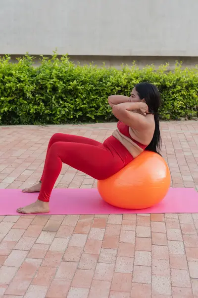 Genç bir kadın arka bahçedeki bir paspasın üzerinde spor yapıyor.