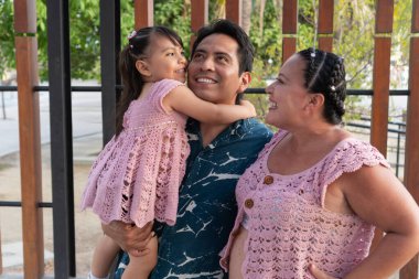 Gülümseyen Aborijinler kızlarını kucağında tutuyorlar, birlikte iyi vakit geçiriyorlar.