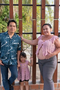 Yeni bir bebek beklerken birlikte poz veren mutlu İspanyol ailesi.