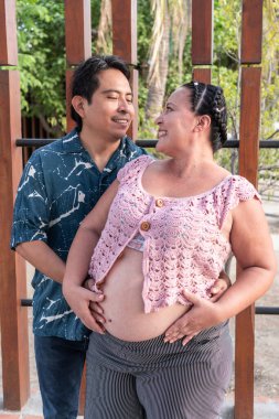 Mutlu İspanyol çift bebek bekliyor, bahçede hamileliğin tadını çıkarıyorlar.