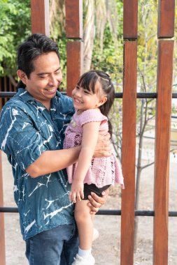 Mutlu İspanyol baba, neşeli küçük kızını kollarında tutuyor, birlikte güzel bir anın tadını çıkarıyor.