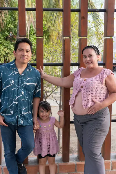 Yeni bir bebek beklerken birlikte poz veren mutlu İspanyol ailesi.