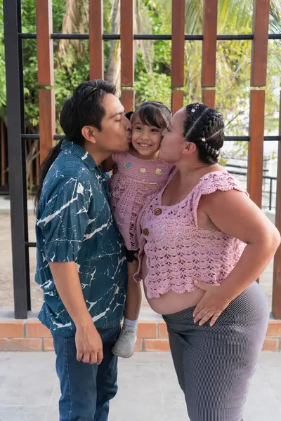 Mutlu İspanyol ailesi bebek bekliyor ve kızlarını öpüyor.