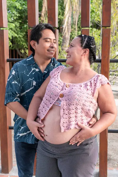 Mutlu İspanyol çift bebek bekliyor, bahçede hamileliğin tadını çıkarıyorlar.