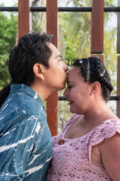 Romantik çift, erkeğin kadını alnından öptüğü, sevgi ve sevgiyi ifade ettiği bir anı paylaşıyor.